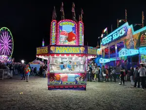 vibrant night fair scene with popcorn stand, neon lights, and crowd captured using a mobile phone